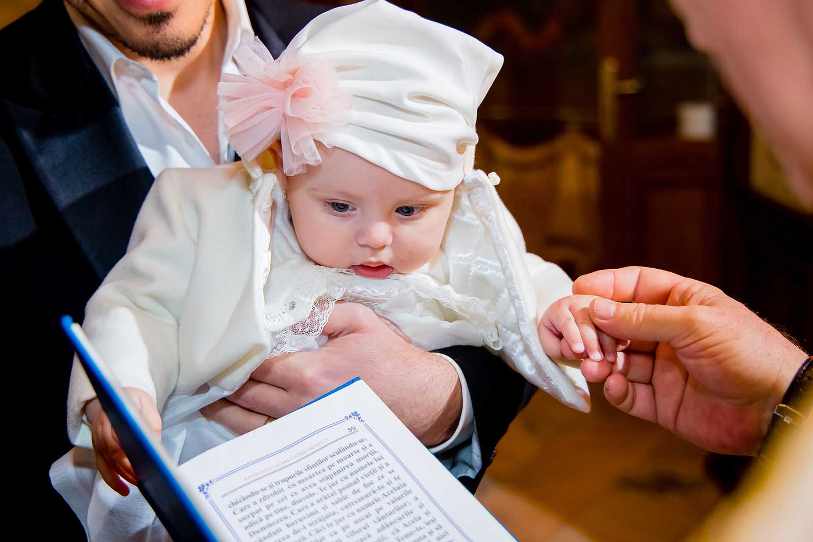 copil tinut de mana de catre preot la botez